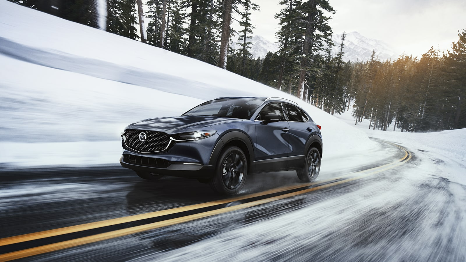 Blue 2023 Mazda CX-30 driving in the snow.