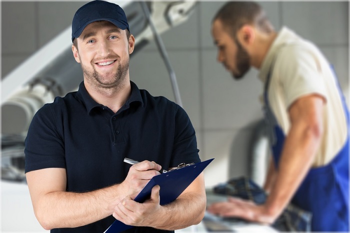 Image of a smiling auto mechanic holding a clipboard.