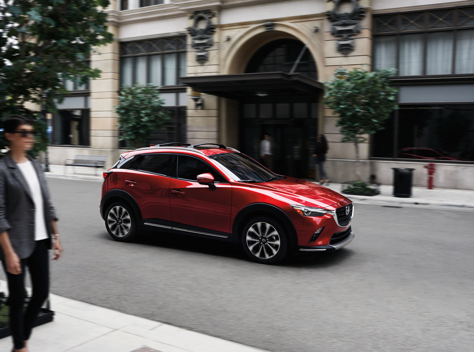 Image of a red 2019 Mazda CX-3 driving down a city street.